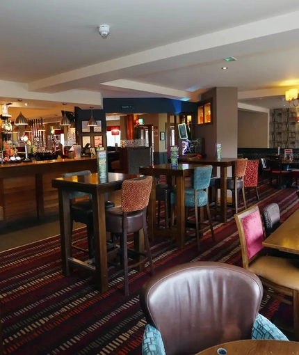 Interior dining area of a pub with a bar and a TV.