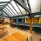 The paved, exterior seating area underneath a large wooden pergola at The Talbot; with a TV on the wall, and string lights hanging above the tables and chairs.