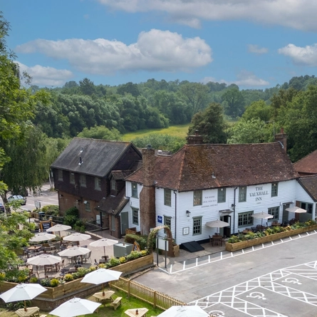 The exterior facade with beer garden seating area, signage and the car park at the Vauxhall Inn.