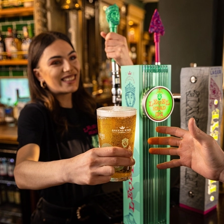 A person handing over a pint of beer