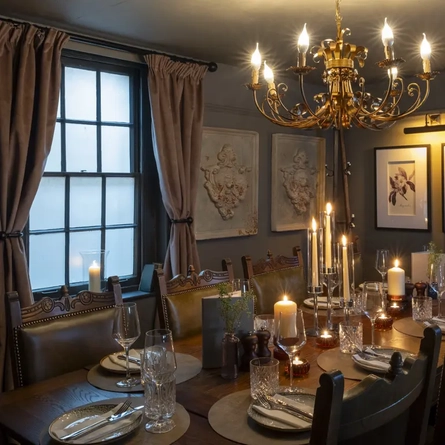 Function room with large table set up for a meal with a chandelier and a large window