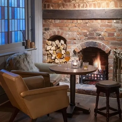 small circle table positioned in front of open fireplace with 2 large cushioned armchairs