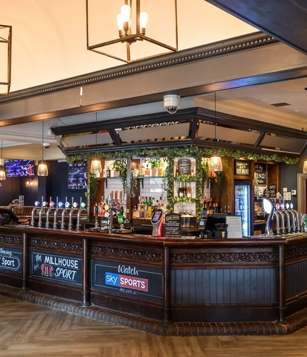 Interior dining area and bar area of a pub with a TV.