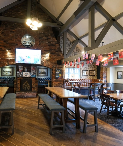 Interior dining area of a pub with a fireplace and a TV.