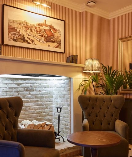 2 armchairs placed in-front of open fireplace with small table 