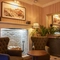 2 armchairs placed in-front of open fireplace with small table 