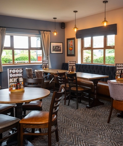 An interior restaurant seating area at The Wall's End, with a long, upholstered booth seat, and a TV on the wall above it.