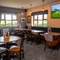 An interior restaurant seating area at The Wall's End, with a long, upholstered booth seat, and a TV on the wall above it.