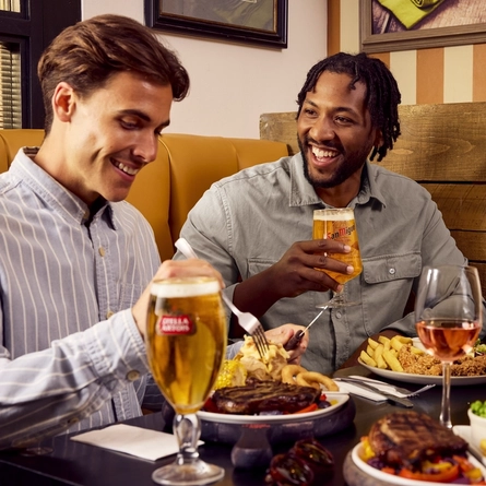 A group of friends all sat round a table with meals and drinks served in the interior restaurant at a Flaming Grill venue.
