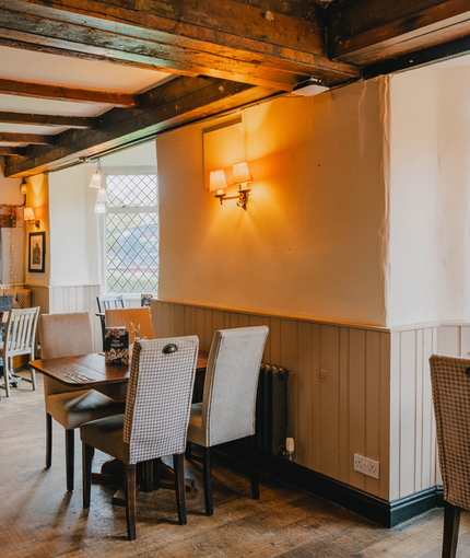An interior restaurant seating area at The Green Man, with an upholstered booth seat, wooden beams, and string lights.