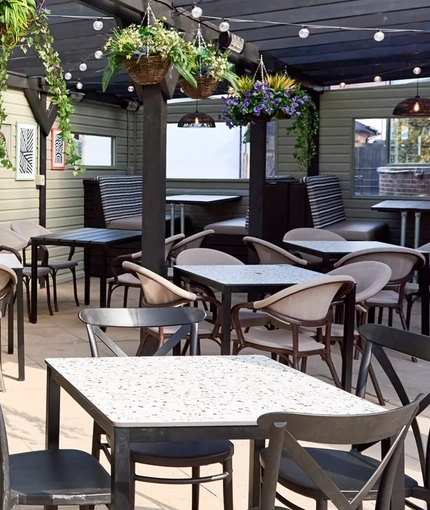 The exterior undercover seating area at The Carousel, with hanging flower baskets and string lights.