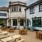 The exterior facade, signage, and beer garden seating area of The White Lion, with wooden picnic tables and string lights overhead. 