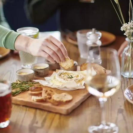 A hand dipping some bread into a camembert board.