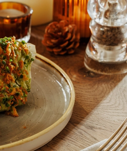 An advertising image of a Schnitzel dish with a glass of white wine within the interior restaurant seating area at The Foundry Bell.
