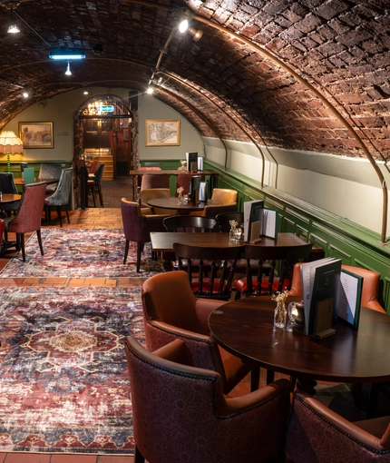 The interior restaurant seating area with tables, chairs, arched brick ceiling and tiled flooring at The Watergates Bar.
