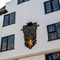 A view looking upwards at the exterior facade of The Golden Lion, with a large black and gold clock on the wall between the upper windows.