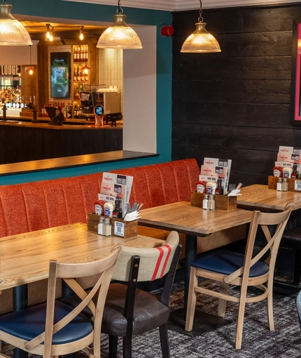 The interior restaurant seating area at The Lodge in Alvaston, with an upholstered booth seat, and a TV on the wall above it.