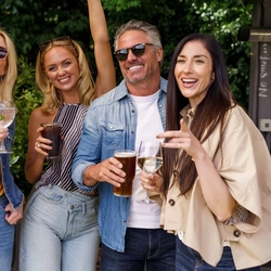 An exterior shot of a group of people with various drinks during the Q3 Live Music Event at one of the Greene King Pubs.