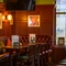 A close up view of restaurant tables and an upholstered corner seat inside The Globe; with framed artwork and a TV on the wood panelled walls above.