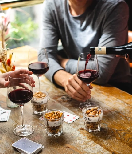 Guests sharing a bottle of red wine and nuts