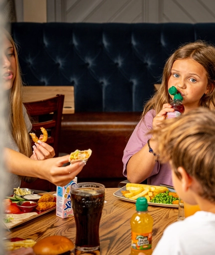 A family sat at an indoor table enjoying a meal and drinks at a Hungry Horse venue.