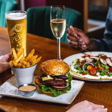 A burger and a pint of beer and a salad and a glass of white wine