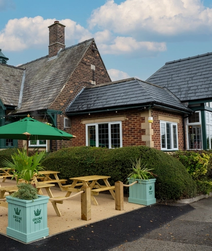 The exterior facade of the venue with hanging baskets, wooden benches and planters at The Church View Inn.