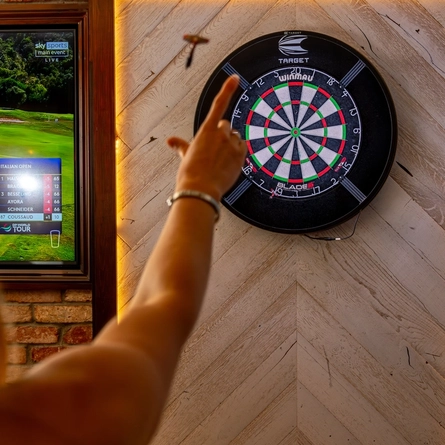 A close up image of a person playing darts within the interior of a Hungry Horse venue.