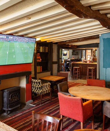 Interior dining area of a pub with a TV and a fireplace.