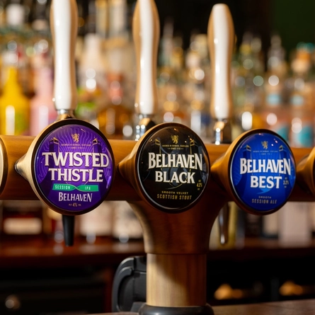 A close up view of the beer taps for Twisted Thistle, Belhaven Black, Belhaven Best, and Estrella Galicia 0.0%, on the bar at The Beehive Inn.
