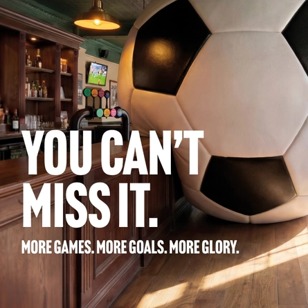 A banner promoting the new football season at Community Social venues. The banner shows an interior of a Community Social-branded sports bar featuring a giant football-shaped wall installation beside the bar. Large white text reads “YOU CAN’T MISS IT.” with smaller text underneath stating “MORE GAMES. MORE GOALS. MORE GLORY.” A television screen showing a football match is visible in the background above beer taps and shelves of bottles.