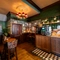 An interior restaurant seating area at the King's Head, with dark wood floors; floral patterned wallpaper and green tiles on the walls; and a coffee machine.