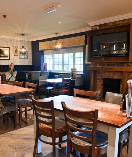 Interior dining area of a pub with a TV and a fireplace.