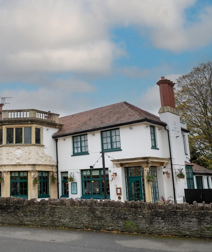 The exterior facade and signage of The White Lion, with a low stone wall in front of the building.