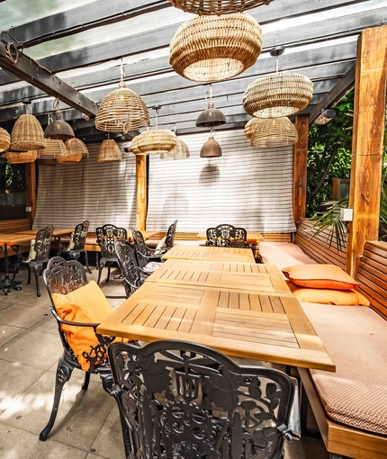 The exterior covered beer garden seating area with tables, chairs, cushioned seating and hanging lighting at The Duke Of Sussex.