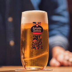An image focusing on a pint of Estrella Galicia on an interior wooden table.