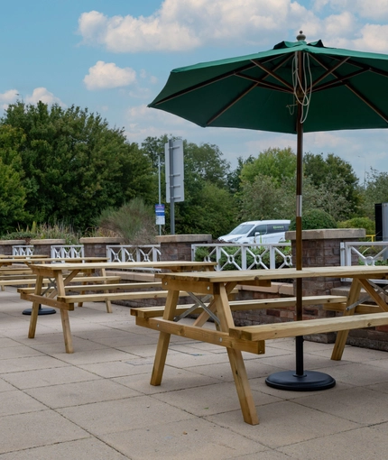 The exterior patio beer garden seating area with wooden benches at The Farmhouse Kitchen Willington.