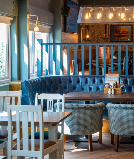 The interior restaurant seating area at The Man On The Moon, with upholstered booth seating, wooden tables and TVs on the walls.