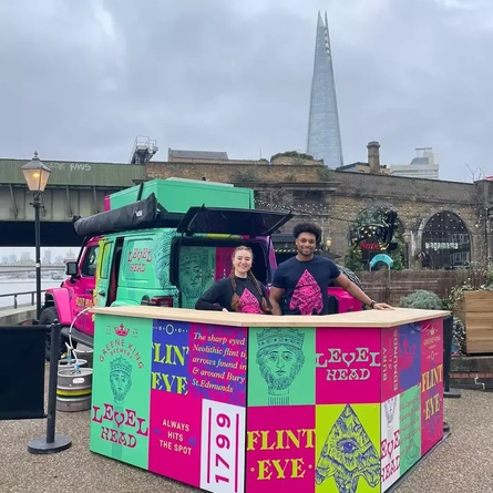 Two team members behind the bar at a Green King pop up shop.
