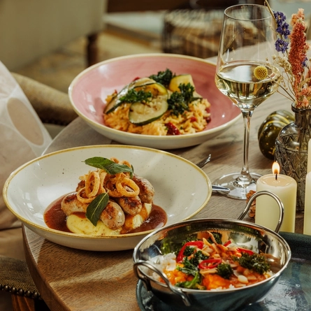 An advertising image of 3 Prefix Main dishes and a glass of white wine within the interior restaurant and seating area at The Foundry Bell.