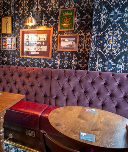 An interior restaurant booth seating area at The White Lion, with upholstered seat, and framed artwork on the wall.