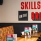 An interior restaurant seating area at The Bramford Arms, with an upholstered booth seat along one side of the room, and the words "Skills on the Grills" on the wall in red and black lettering.