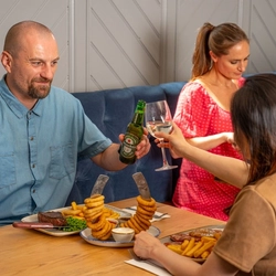 An image of a group of people enjoying various mains dishes and drinks within the interior restaurant seating area at a Hungry Horse venue.