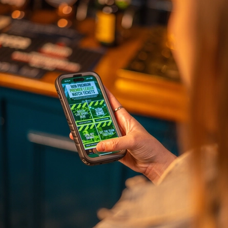 a woman showing the Greene King pubs app from her phone