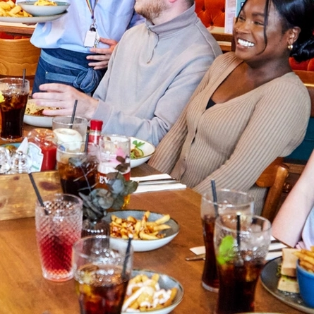 A group of people seated at a table with food and drink in front of them.
