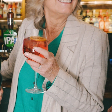 A group of friends holding low and no drinks in a cheers at a Greene King venue.