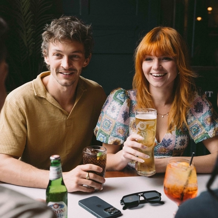 A group of friends sat around a table in the seating area of a Greene King venue enjoying drinks on a £3 deal.