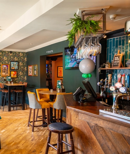 The bar and interior restaurant seating area at The Windmill In in York, with padded chairs and bench seats, and TVs on the walls.