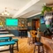 The bar and interior restaurant seating area at The Windmill In in York, with padded chairs and bench seats, and TVs on the walls.