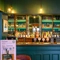 A close up view of one of the wood panelled bars inside The Globe; with golden drinks trays on the counter, and bottles of wine and alcoholic spirits on illuminated shelves behind the bar.